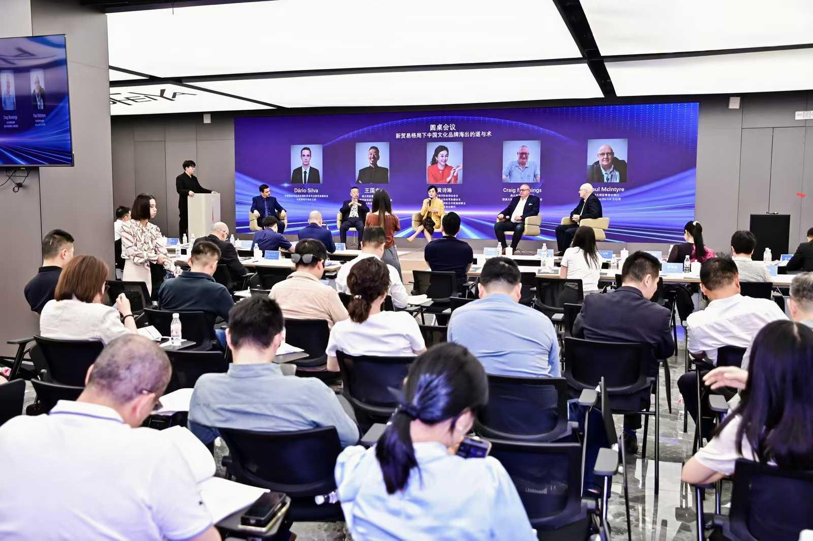 Panel discussion on stage with an audience seated in a conference room.